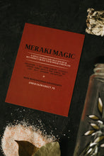 Load image into Gallery viewer, A red rectangular card titled 'MERAKI MAGIC' lies on a dark textured surface, surrounded by bay leaves on coarse salt, a sage bundle, and a glass container.
