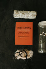 Load image into Gallery viewer, A flat-lay of a cord cutting kit on a dark textured background, featuring a sage bundle wrapped in string, an orange instruction card titled 'CORD CUTTING', a pile of salt, a black cord, and a glass jar with a white lid.
